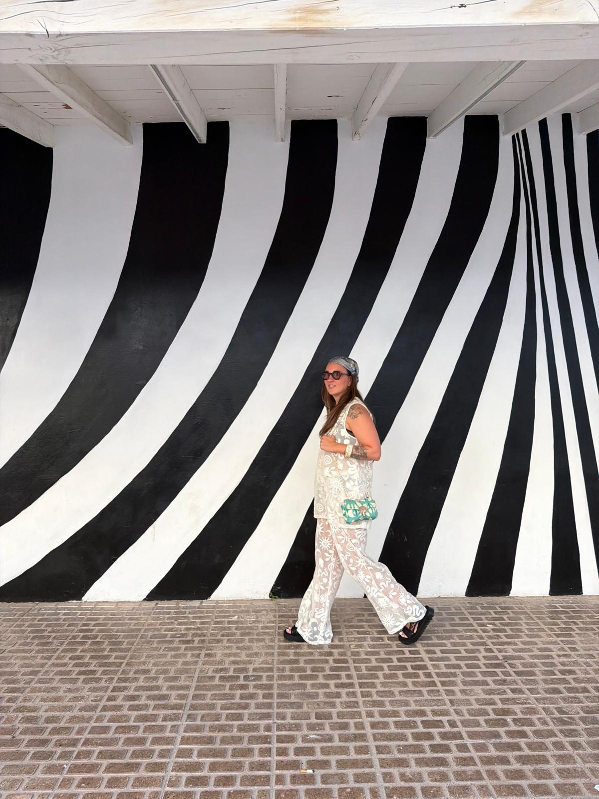 Loanah marchant devant une fresque murale op-art noir et blanc
