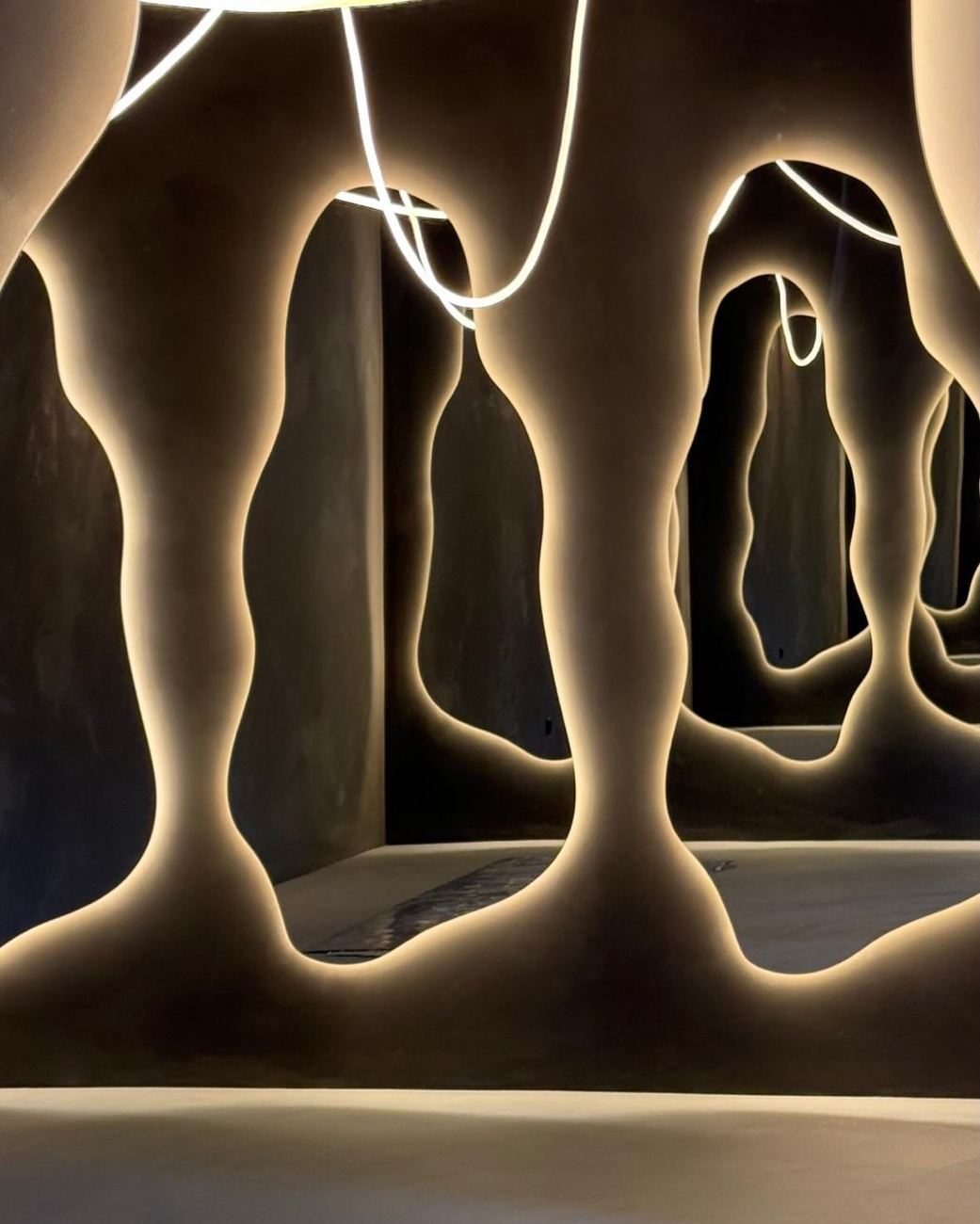 Enfilade de miroirs organiques rétroéclairés, murs en enduit minéral sombre — Studio Clo