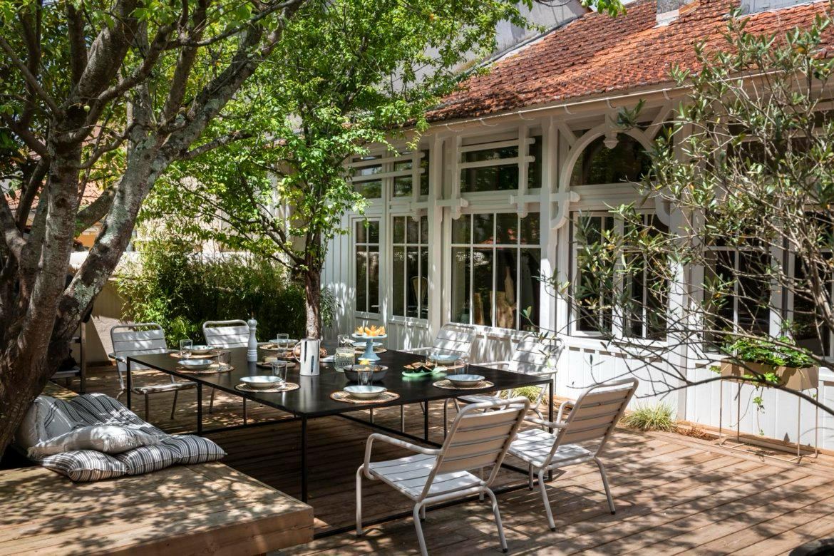 Terrasse en bois sous l'arbre, grande table noire dressée — Maison Lehmann